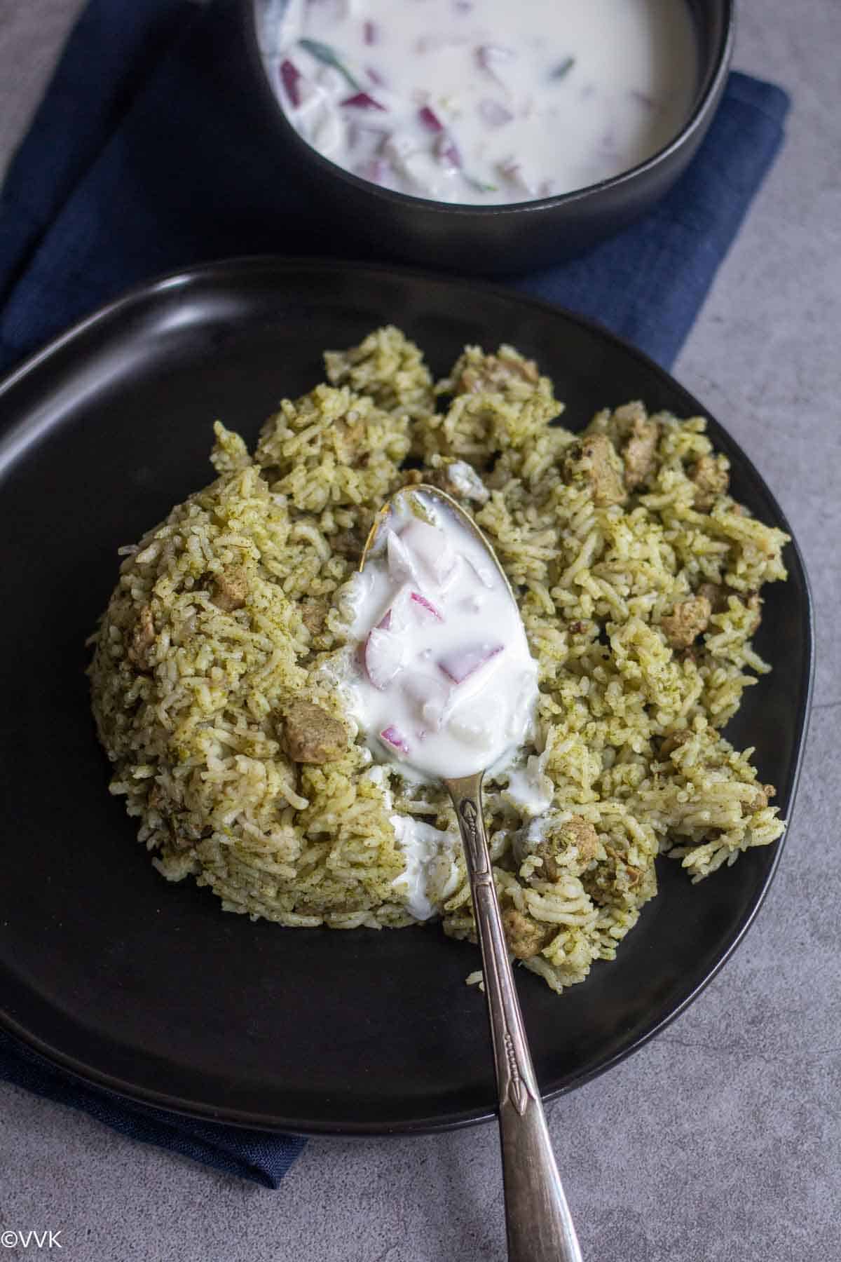 soya mint pulao in black plate with raita on top