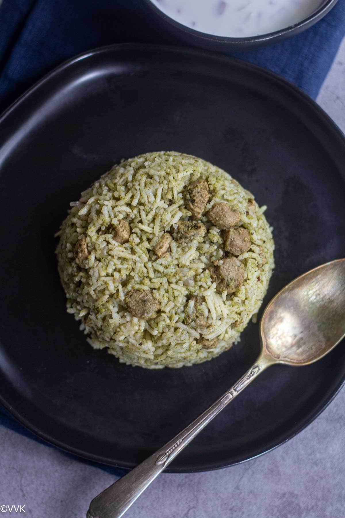 close up shot of soya mint pulao served on black plate with spoon on side