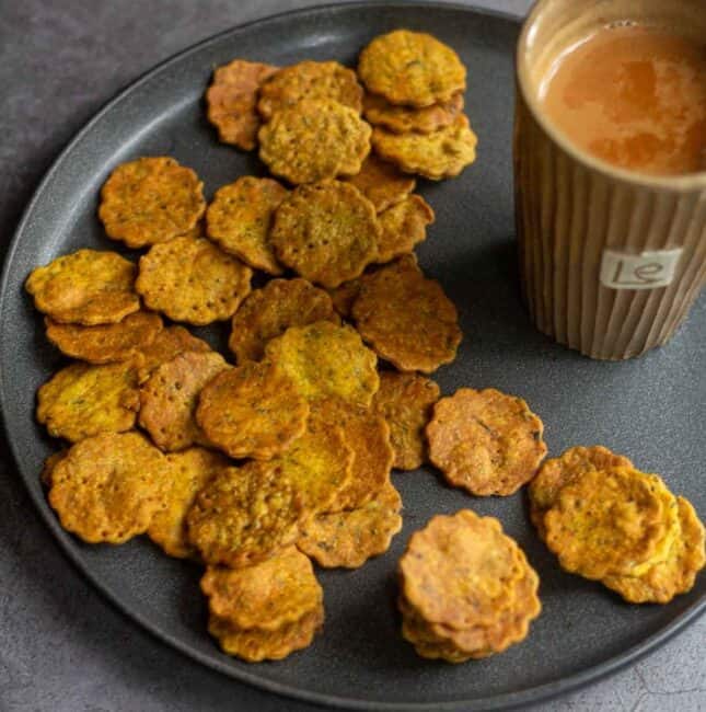 square image of baked methi mathri served with tea