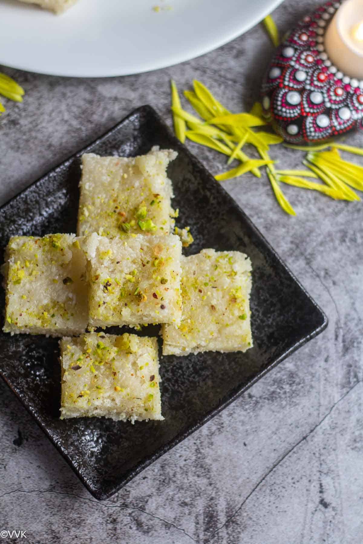 overhead shot of stacked thengai burfi in black plate
