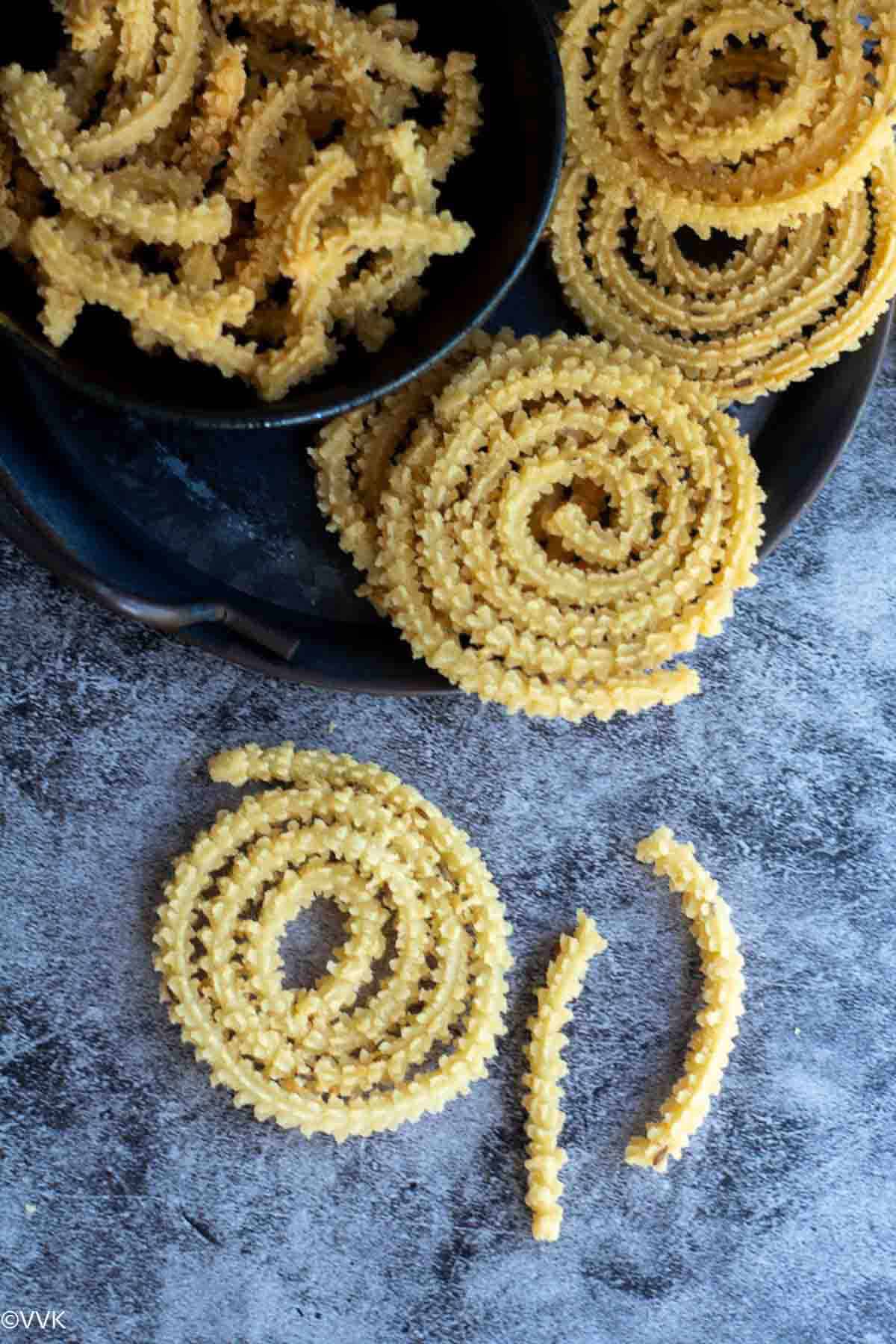 close up shot of single butter murukku and other  murukku behind this one 