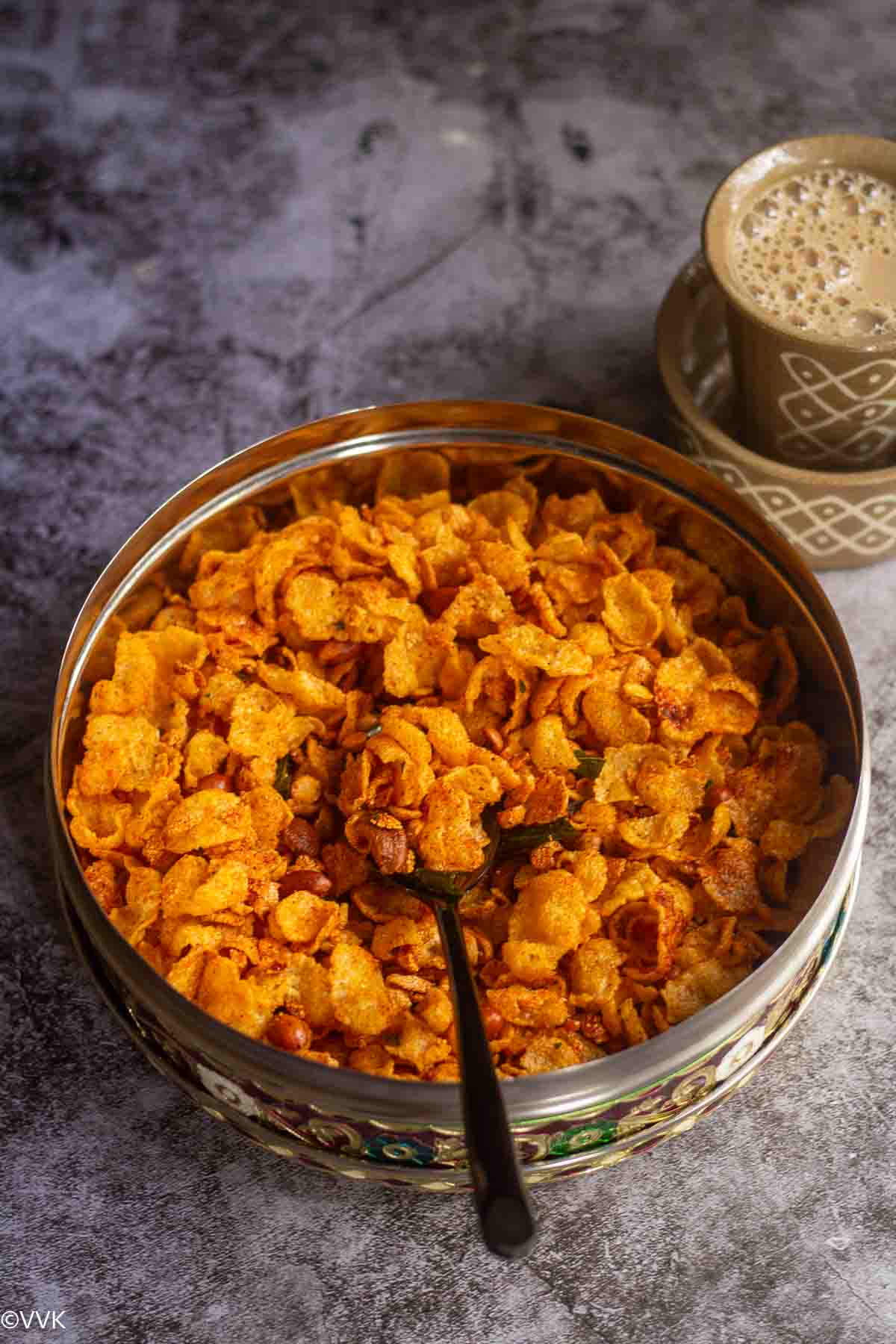 corn mixture in a stainless container with a spoon inside served with coffee