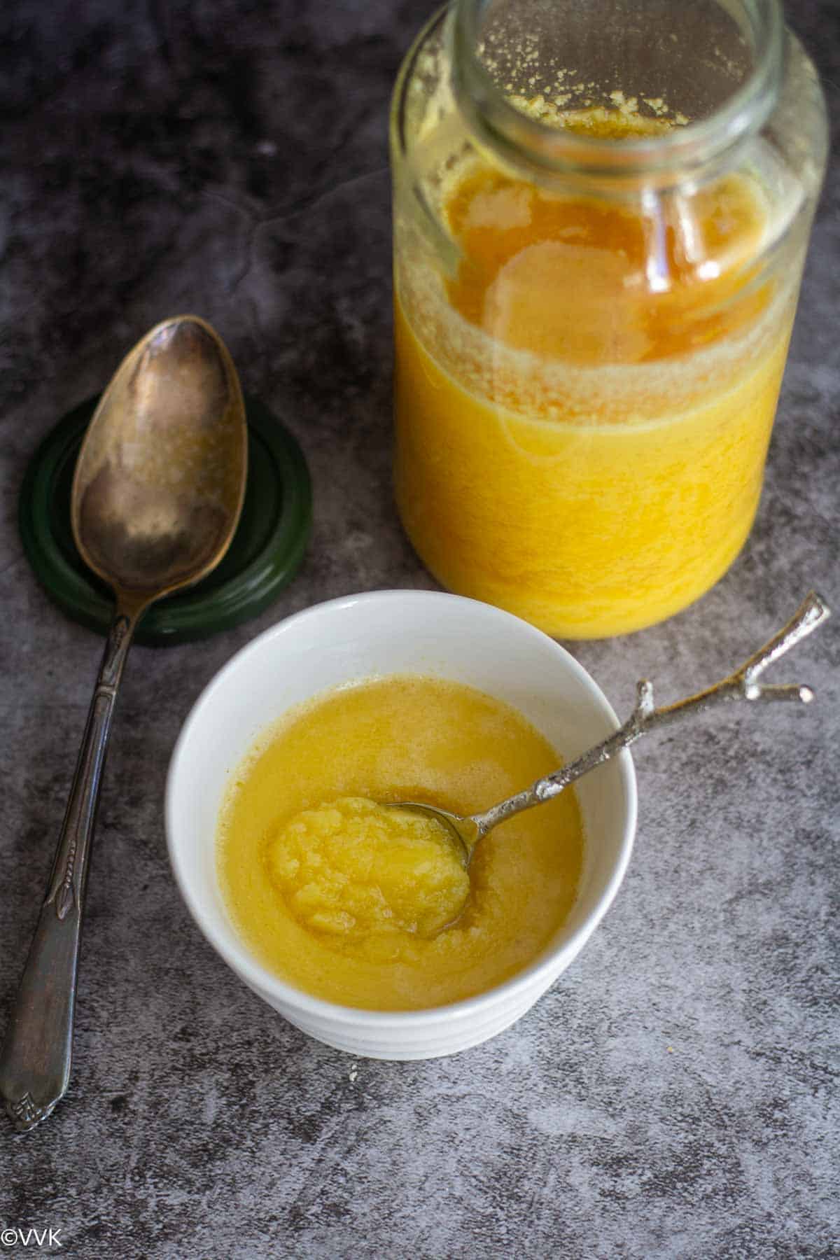 solidified ghee in a a bottle and bowl with spoon inside