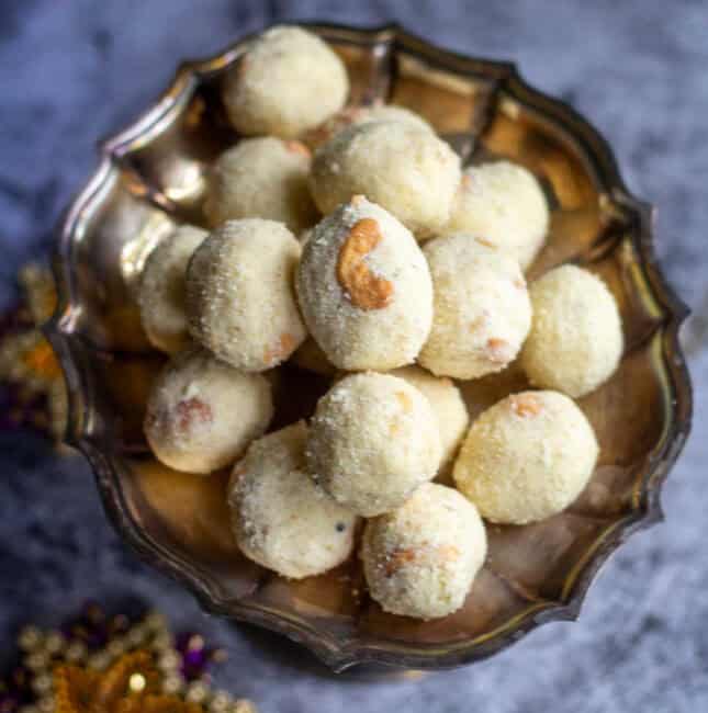 square image of rava laddu stacked in a silver plate