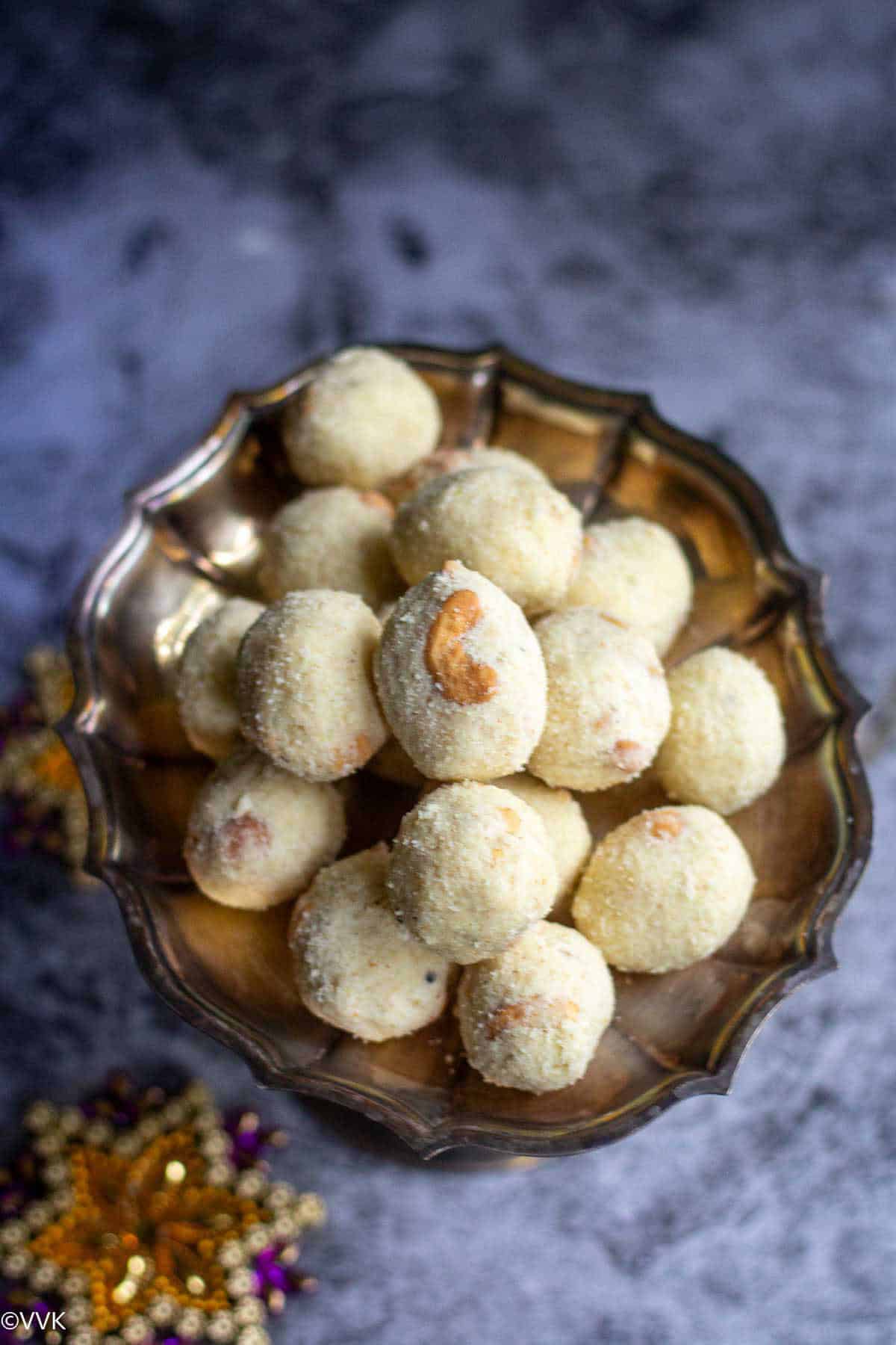 close up and overhead shot of rava laddu stacked in a silver stand