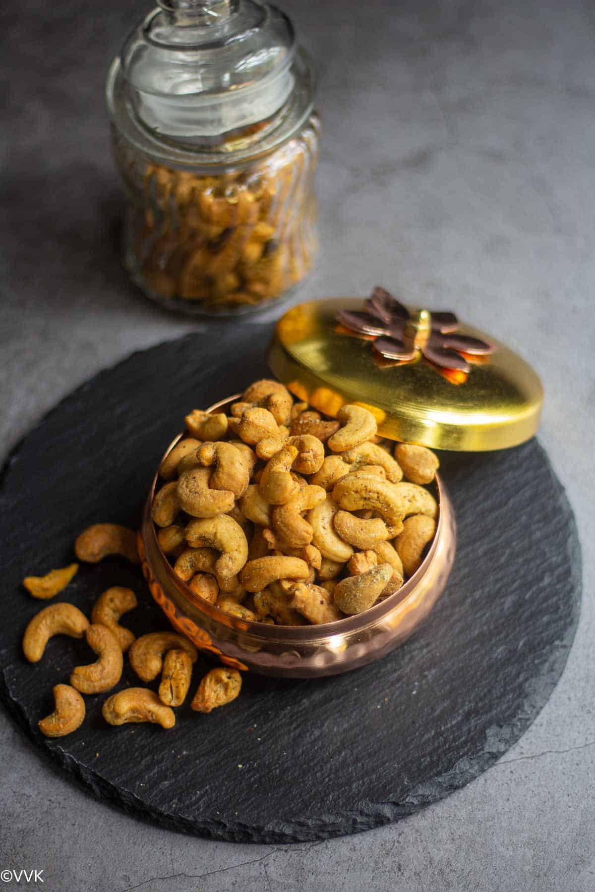 air fryer roasted cashews in gifting bowl along with some in jar placed on black slate