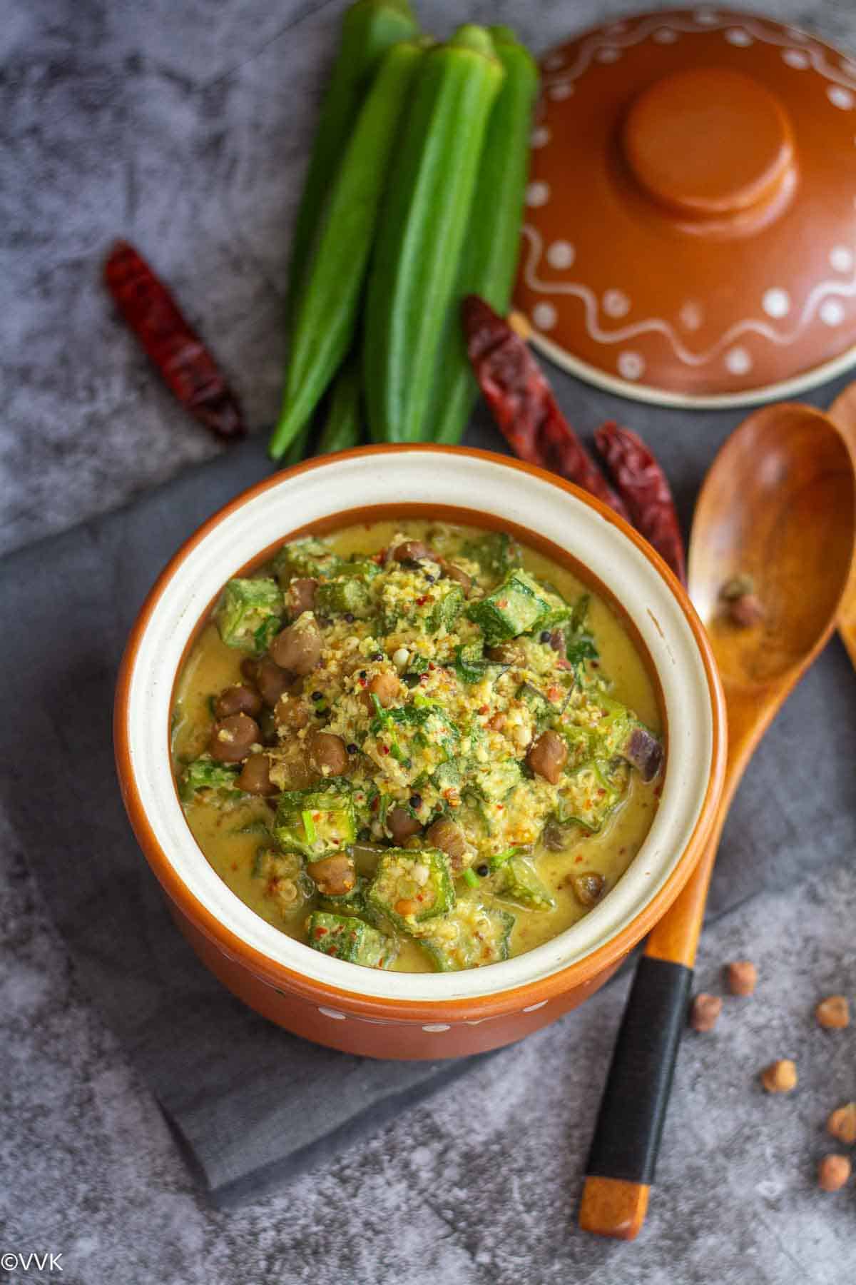 overhead shot of vendakkai kootu with some okra and red chilies on the side