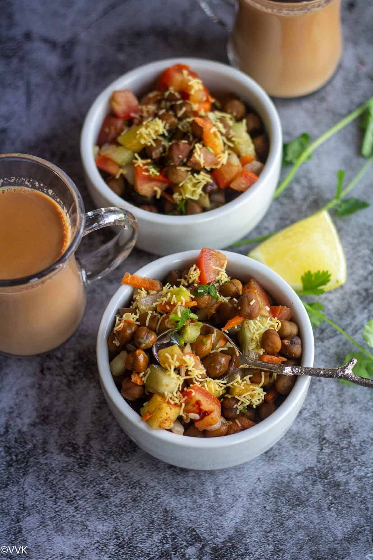 close up shot of black chickpeas chaat with spoon inside on one bowl served with tea