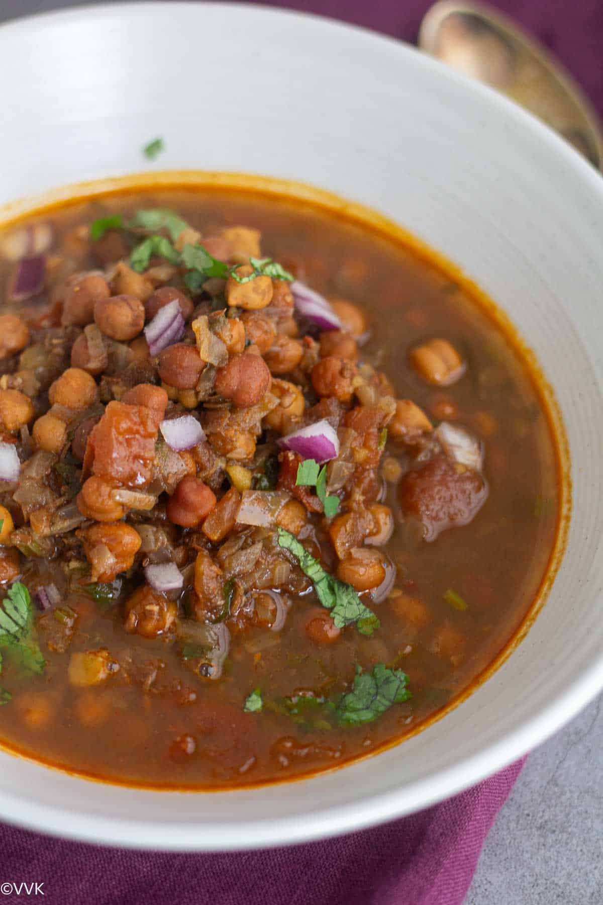 close up shot of instant pot black chickpeas stew with raw onions drizzled