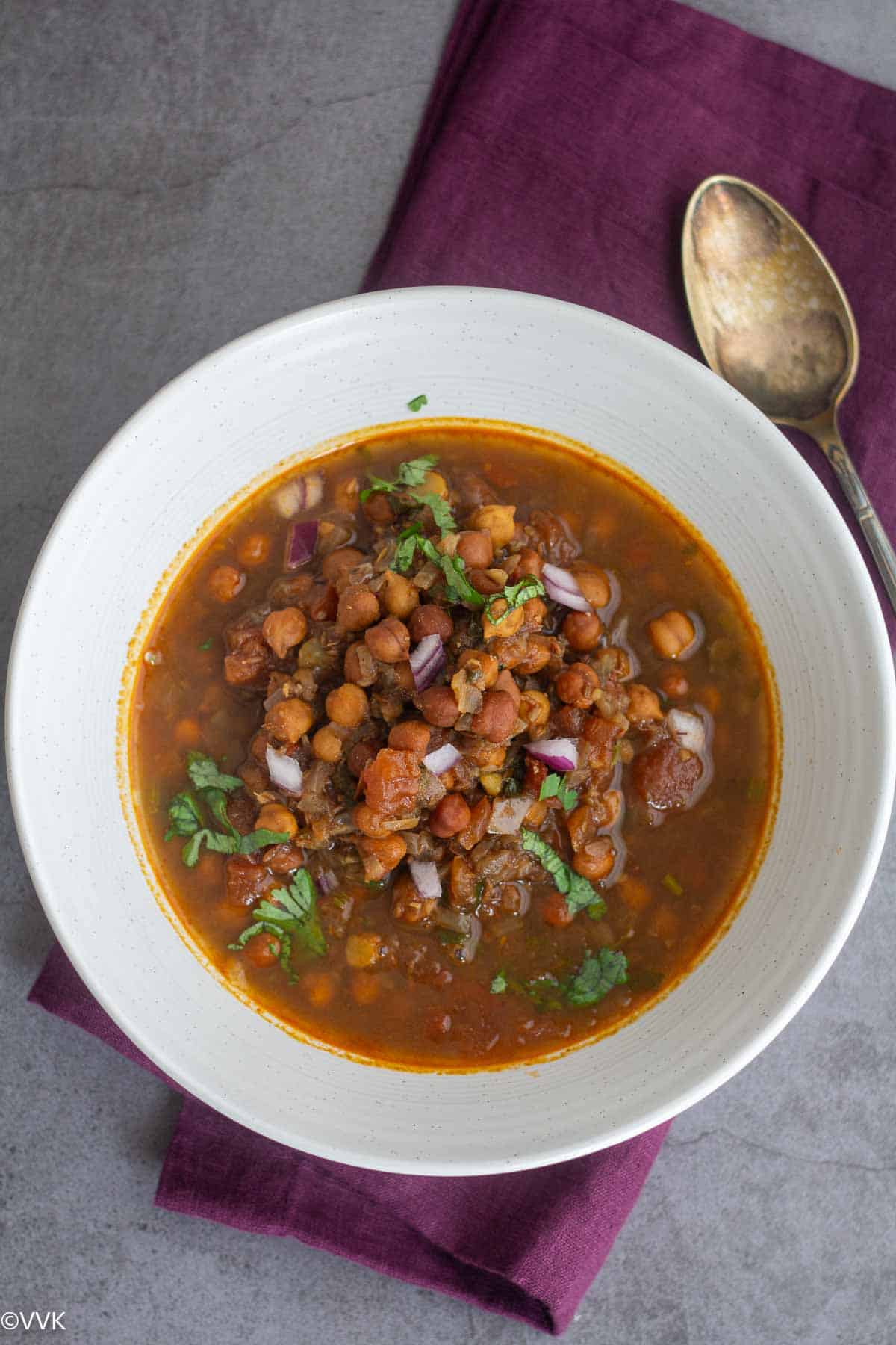 overhead shot of Bihari ghuni served in white bowl with chopped onion and cilantro sprinkled.