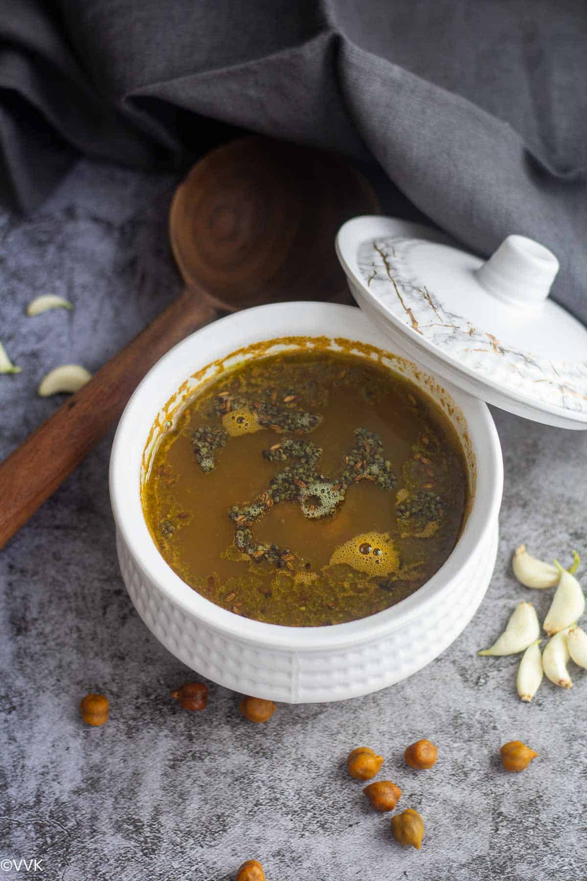 black chickpea stock rasam with chickpeas and garlic on the side