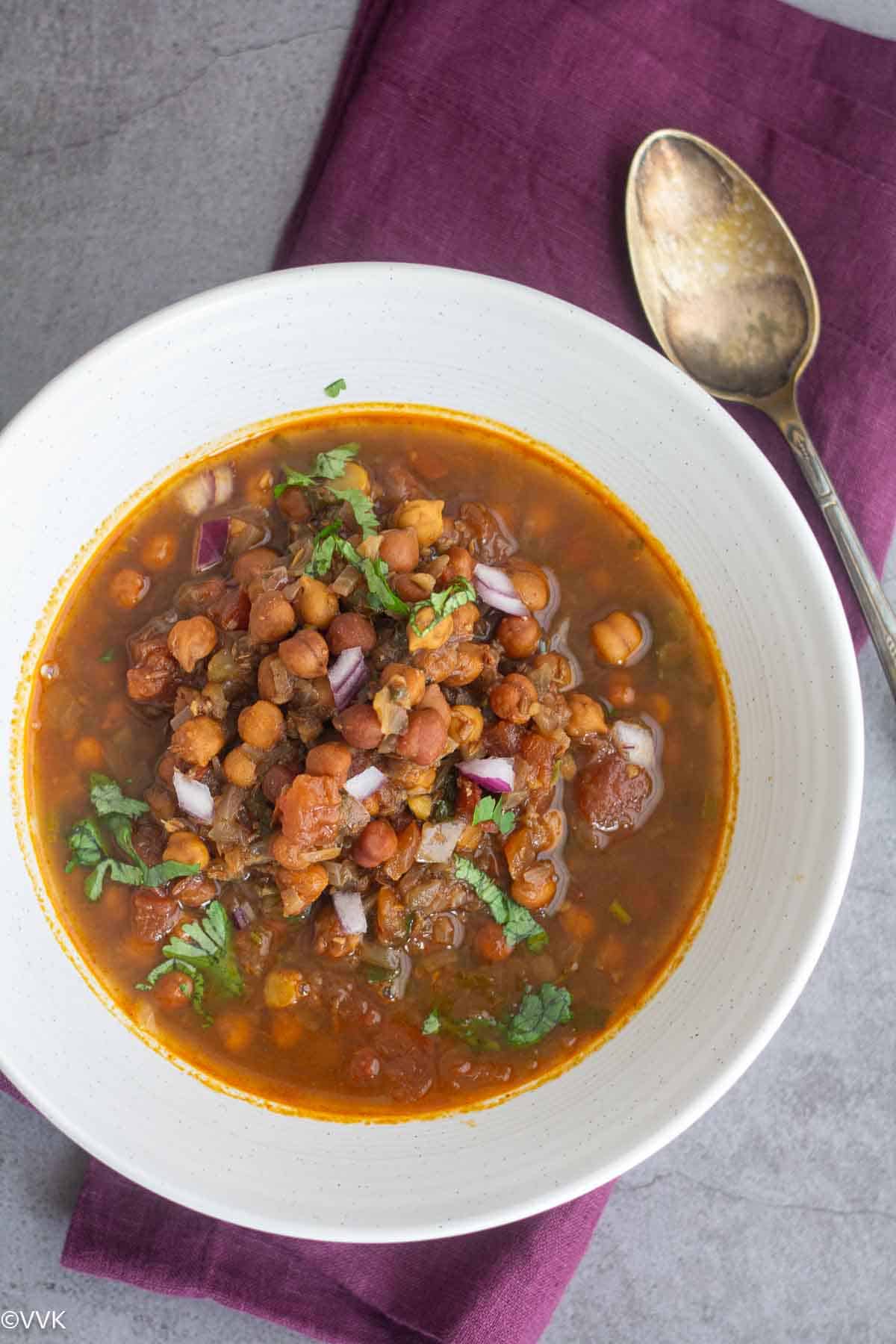 overhead shot of instant pot ghugni served in white bowl with a spoon on the side