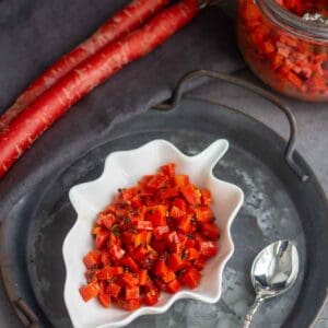square image of carrot pickle served in a leaf bowl