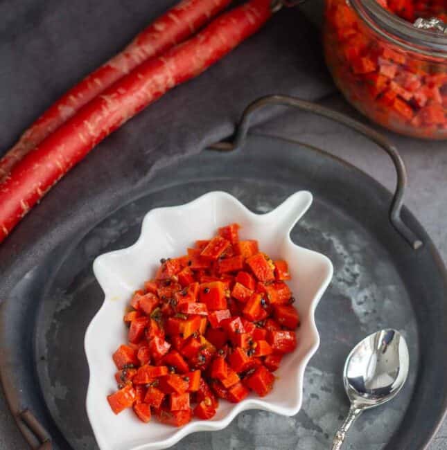 square image of carrot pickle served in a leaf bowl