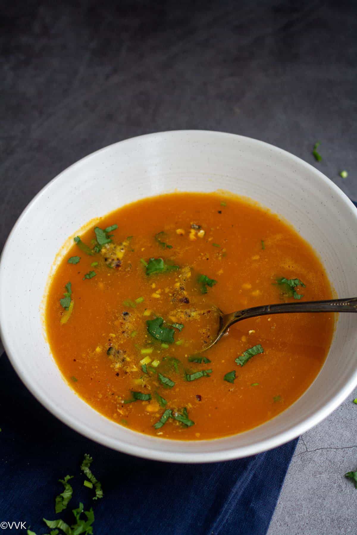 carrot soup garnished with cilantro and nuts with a spoon inside