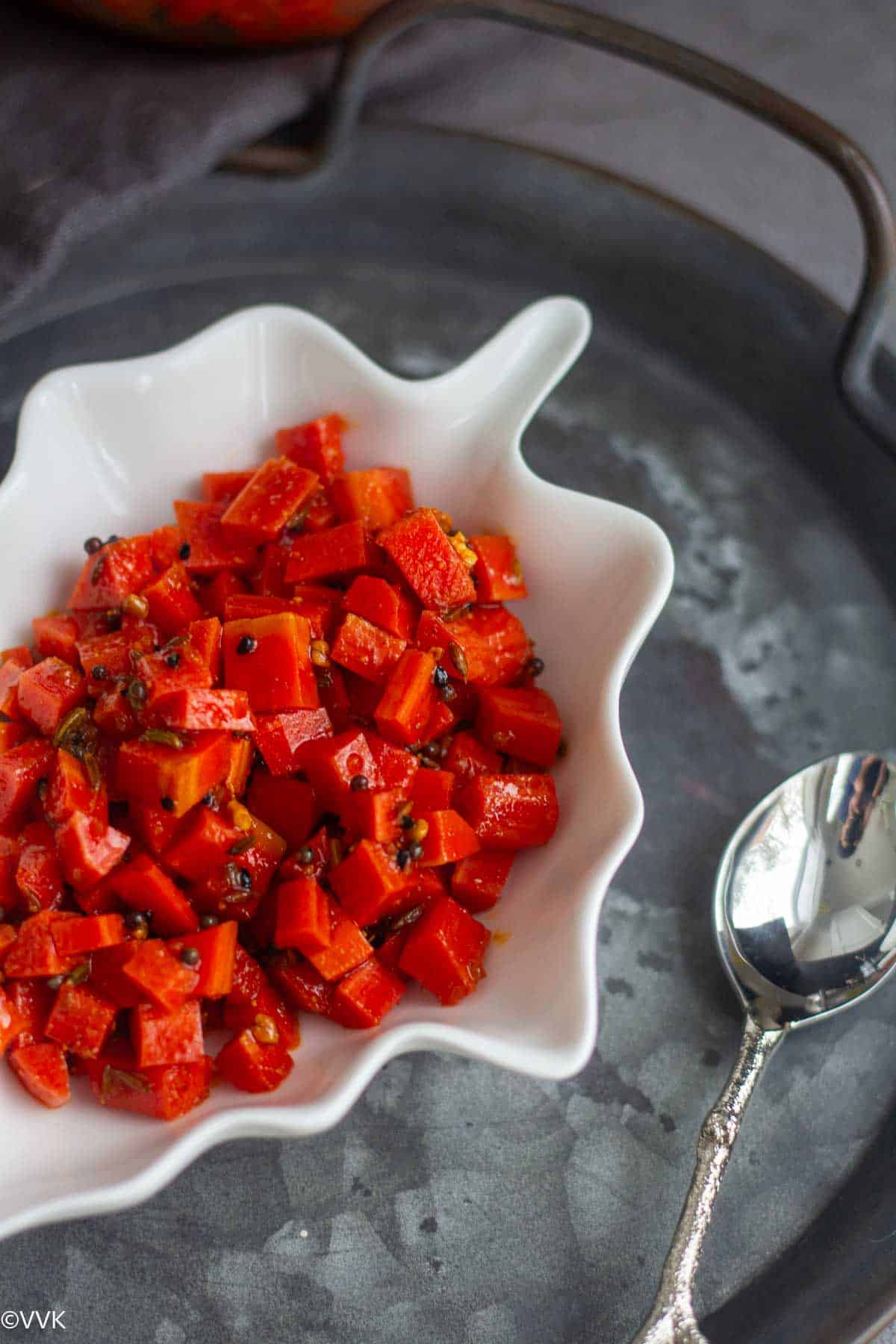 close up shot of carrot pickle with a spoon on the side