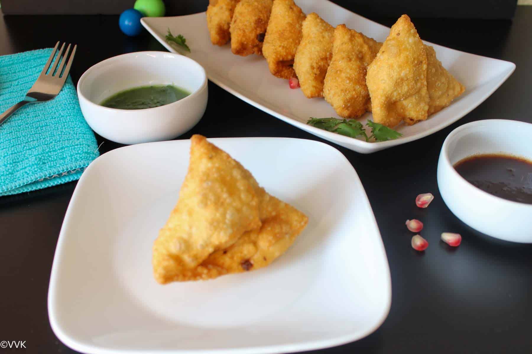 deep fried single samosa in one plate and remaining samosa lined up in another plate