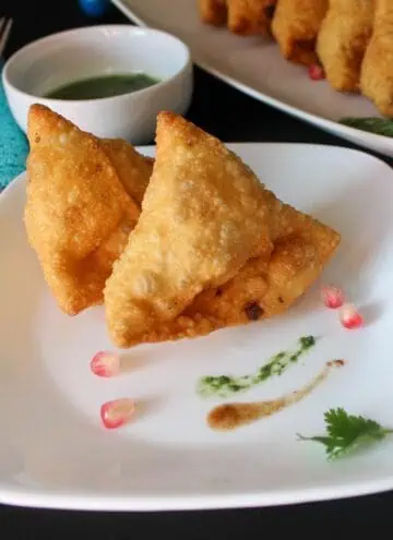 square image of two samosa placed on white plate