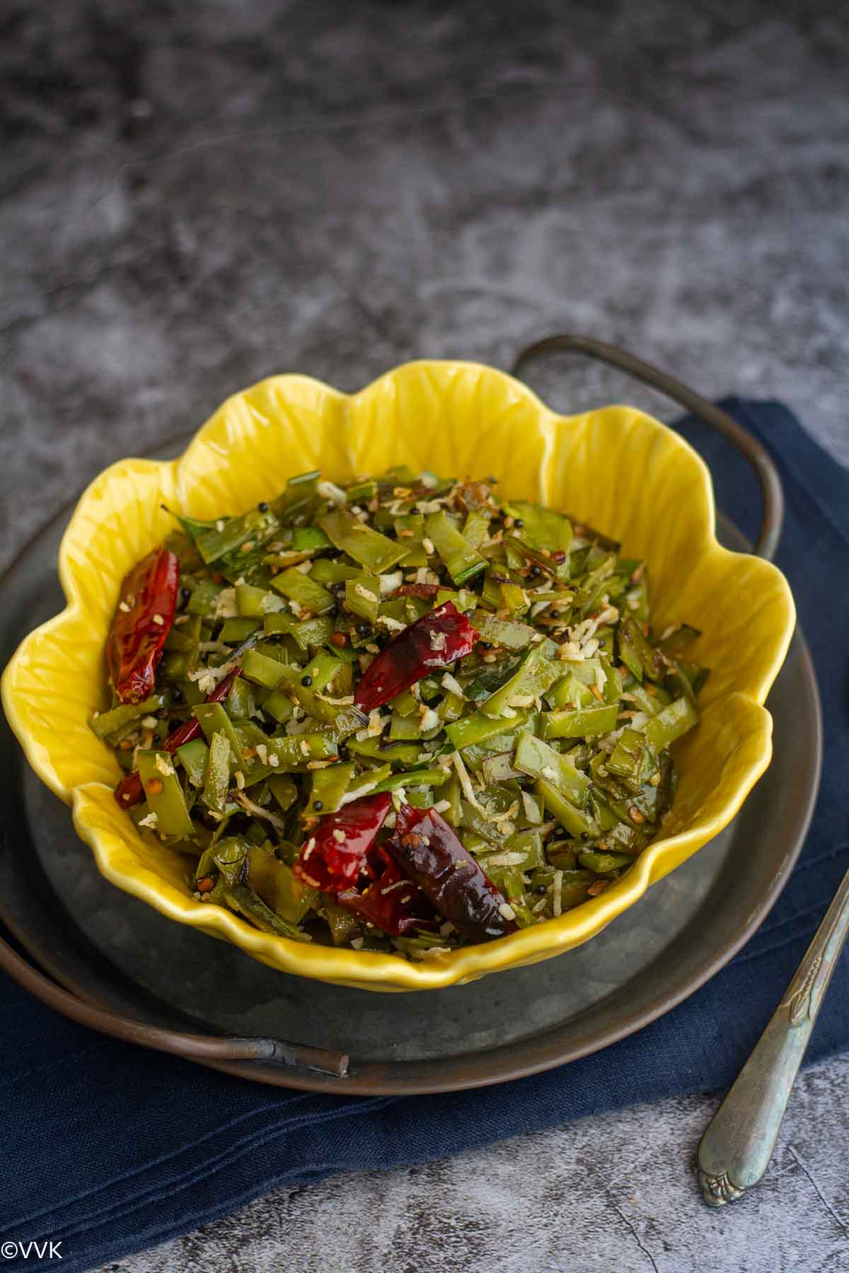 snow peas poriyal served in yellow bowl placed on a tray and towel
