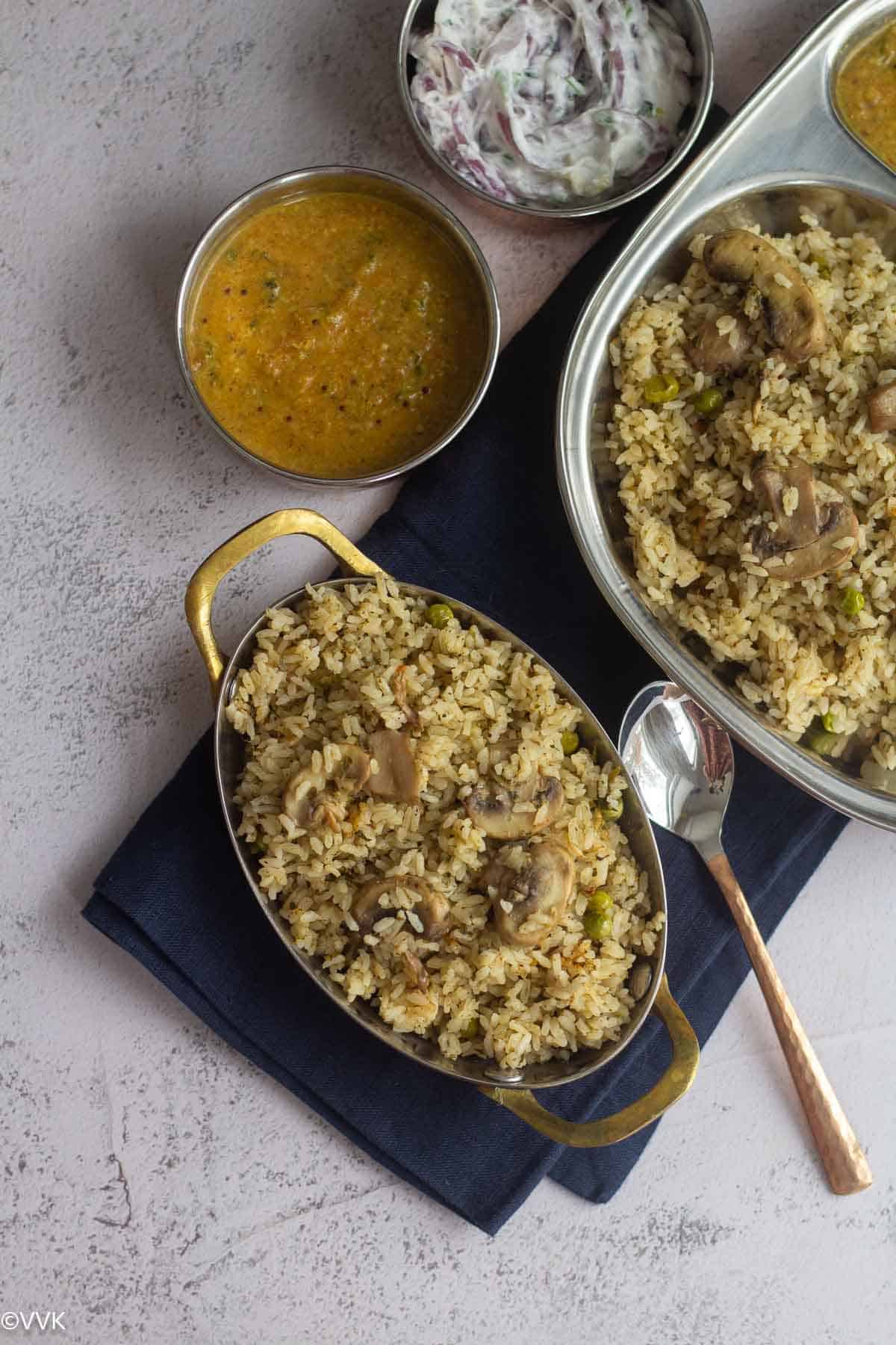 overhead shot of mushroom biryani served in copperware