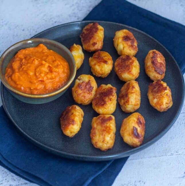 square image of baked tater tots with marinara sauce