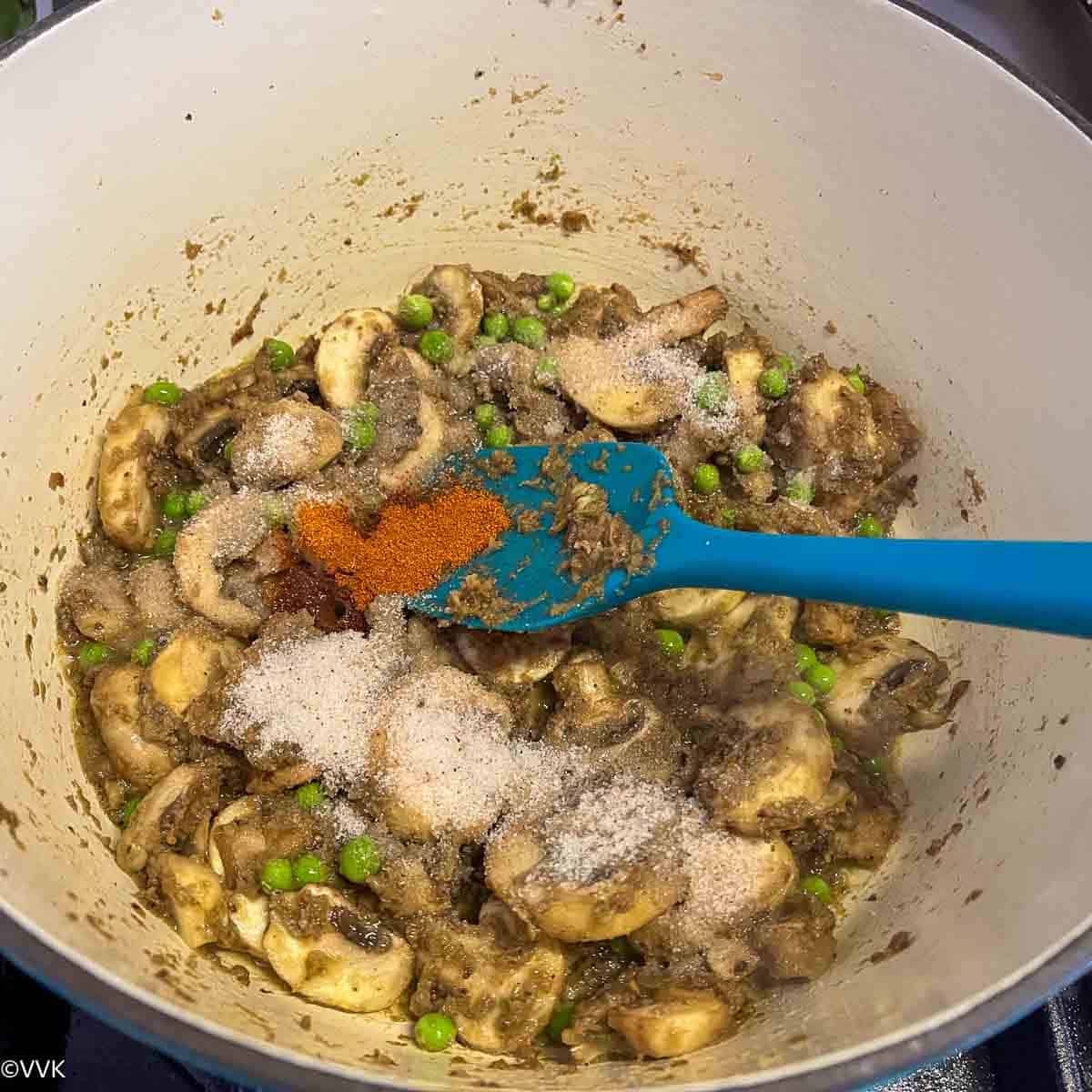 adding salt and chili powder to the biryani
