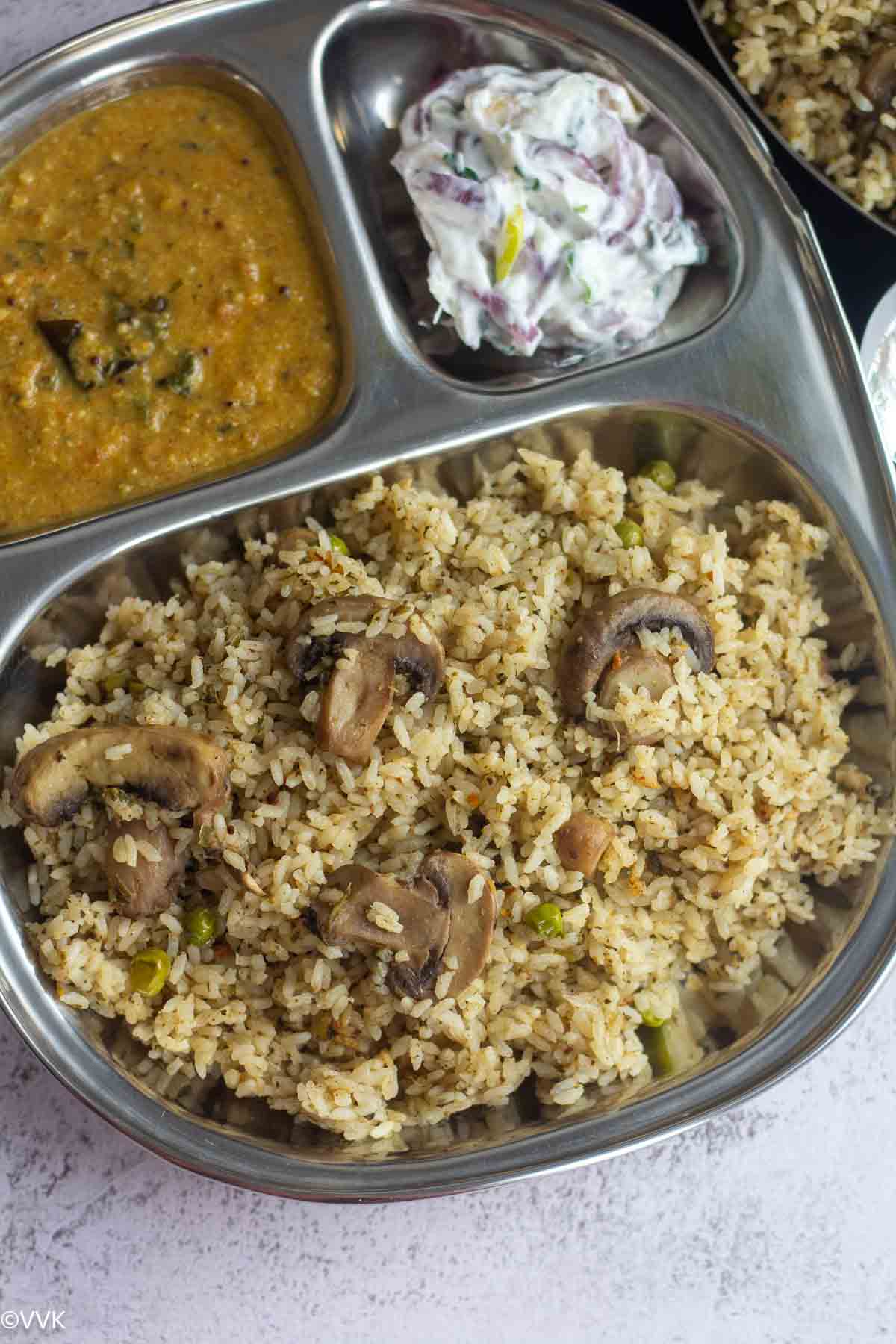 close up shot of veg dindigul style mushroom biryani served in partioned plate
