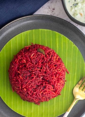 square image of beets pulao served in banana leaf placed on a plate