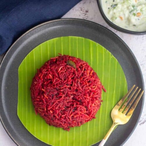 square image of beets pulao served in banana leaf placed on a plate