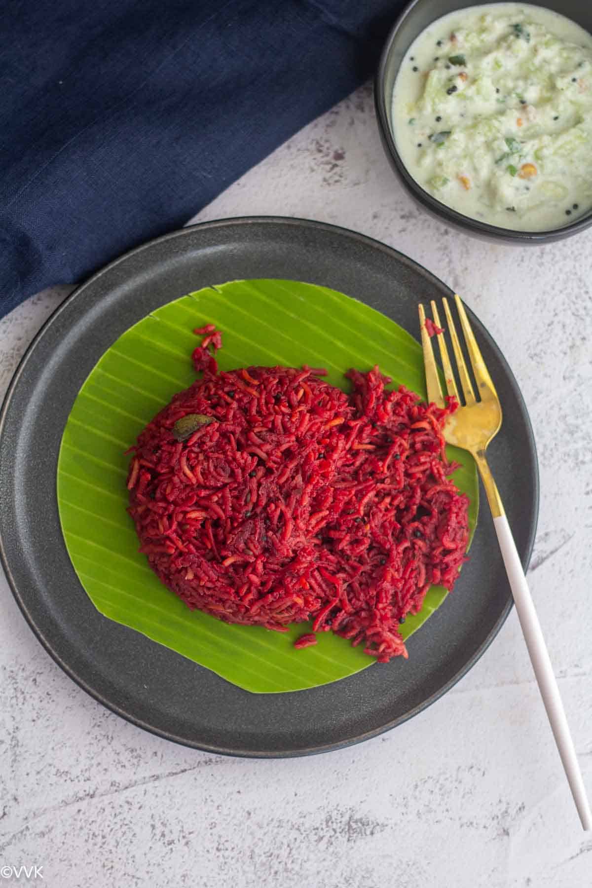 beetroot pulao in a plate broken with fork served with raita