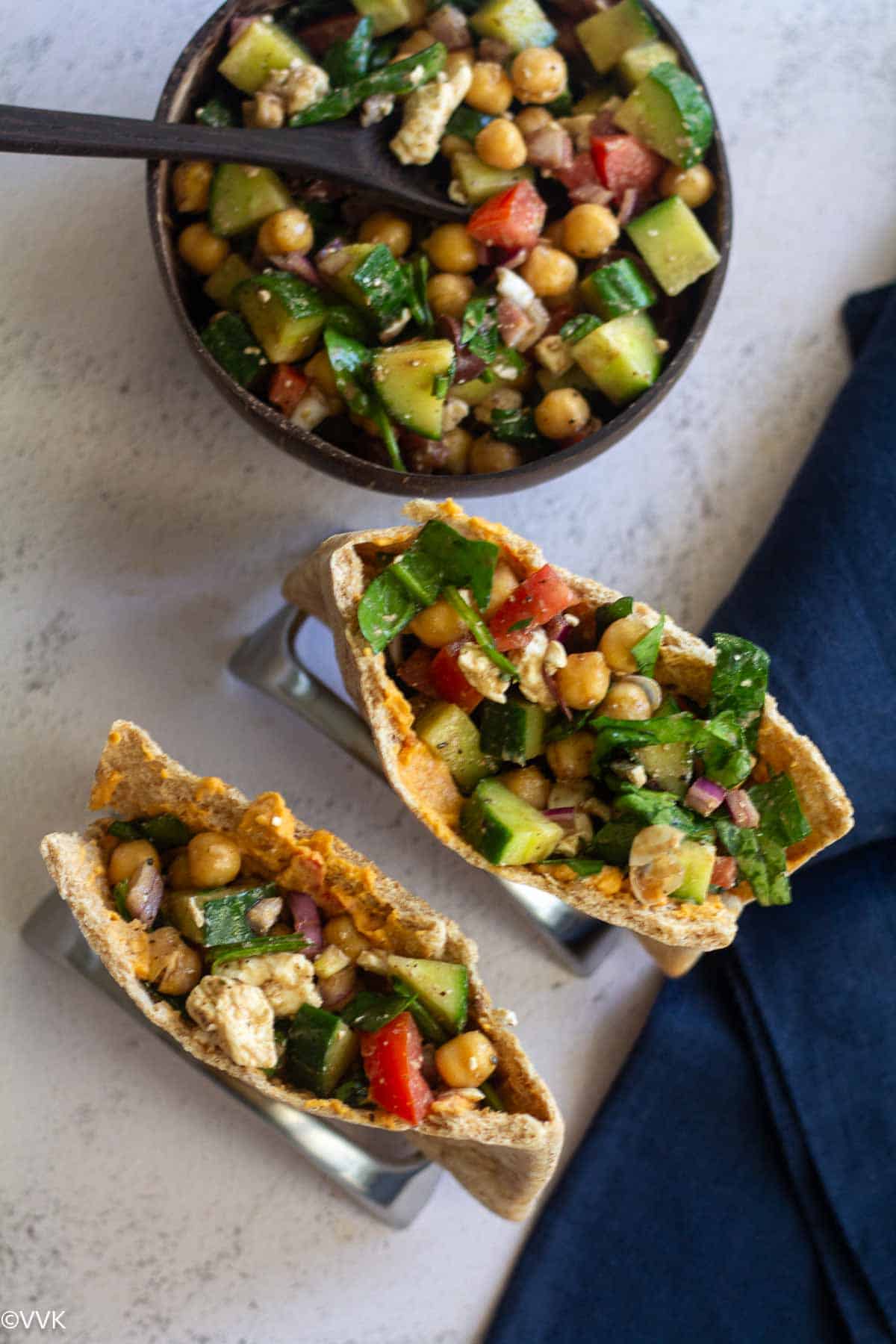 overhead shot of mediterranean chickpeas salad served in two pita bread and also in a coconut shell bowl