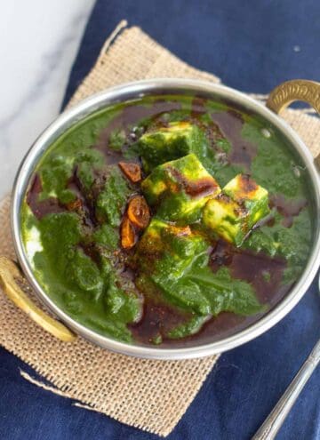 square image of palak paneer served in kadai bowl placed on jute fabric