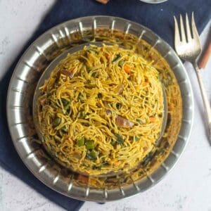 square image of semiya pulao placed on steel plate with a fork on the side