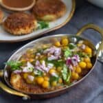 square image of white peas curry and aloo tikki served in copperware