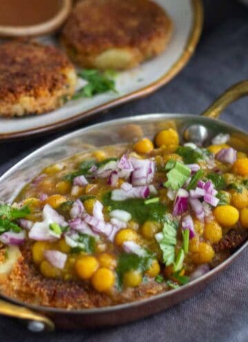 square image of white peas curry and aloo tikki served in copperware
