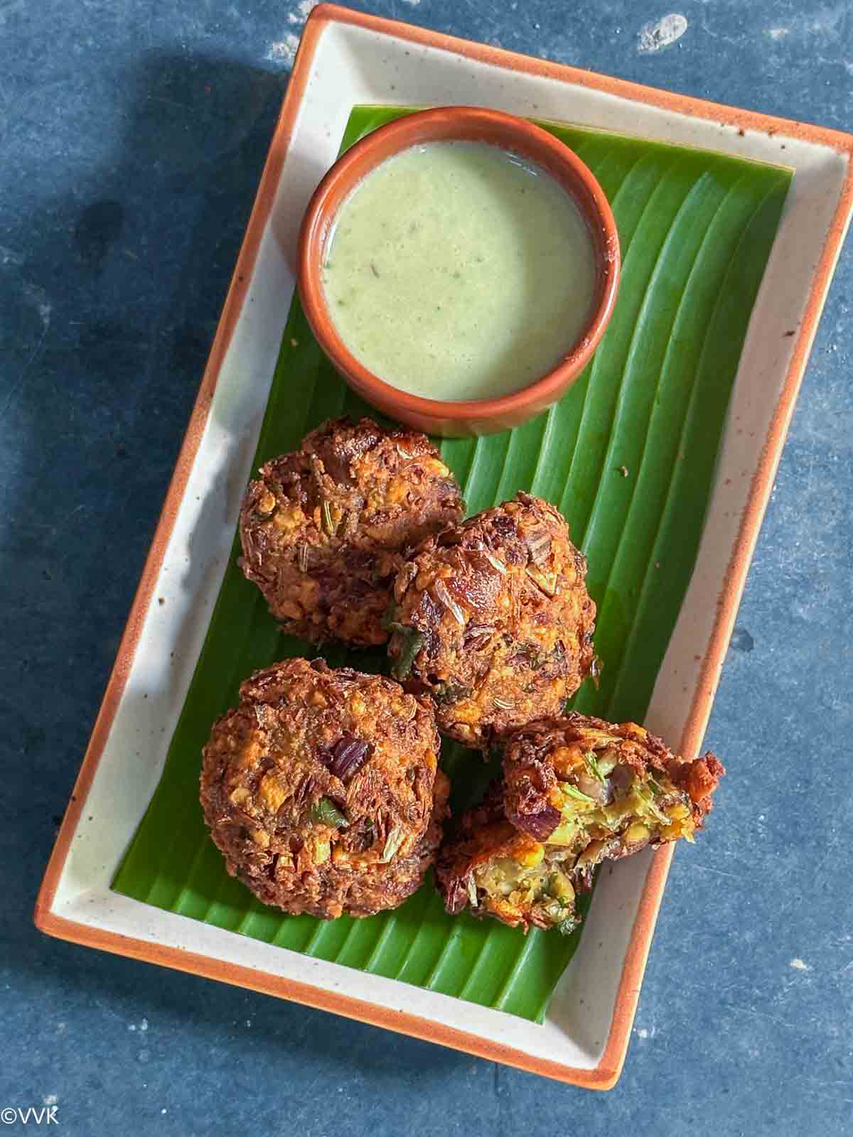 vazhai poo vadai with one vadai broken into two pieces served with chutney in a plate