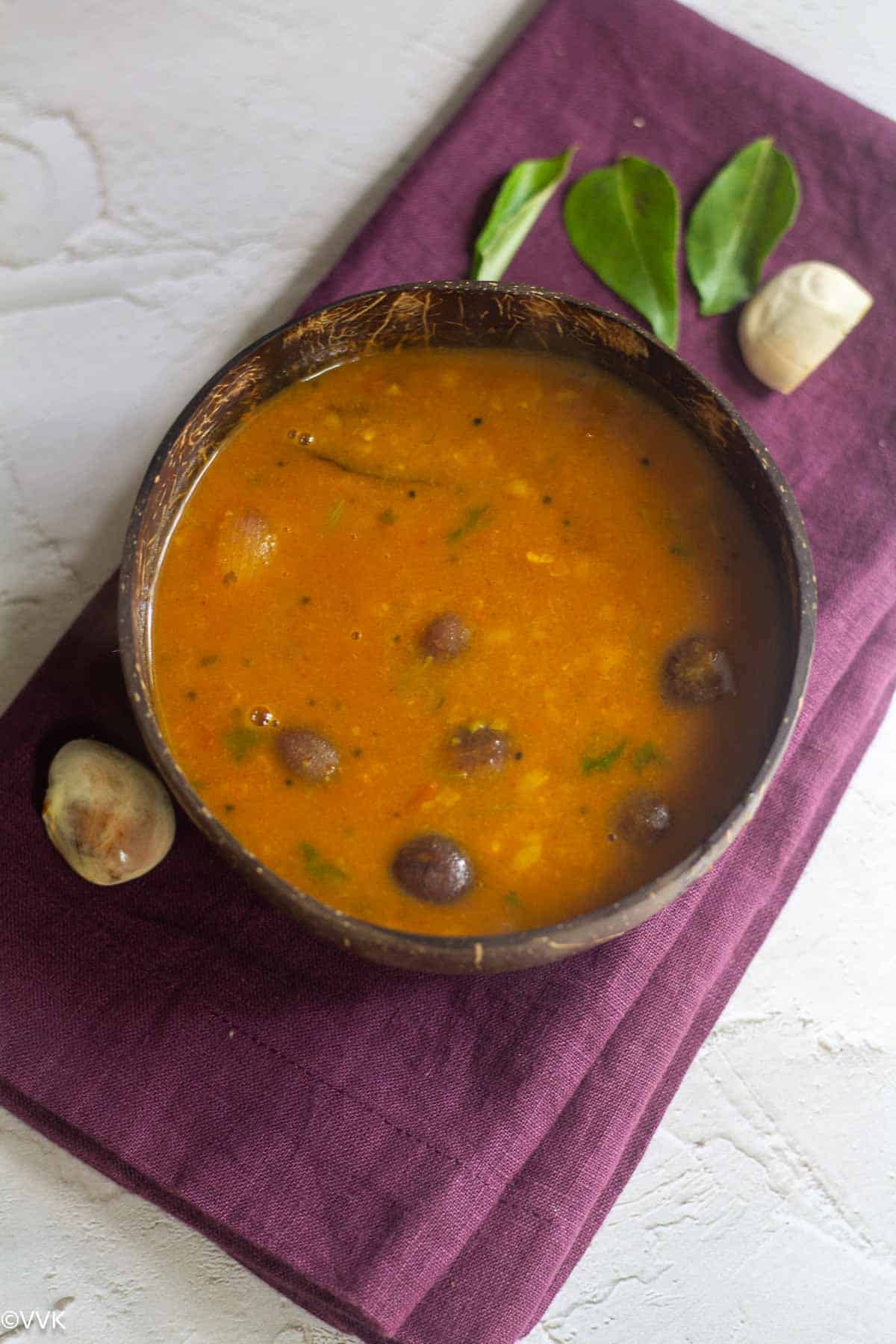 overhead shot of palakottai sambar served in coconut bowl