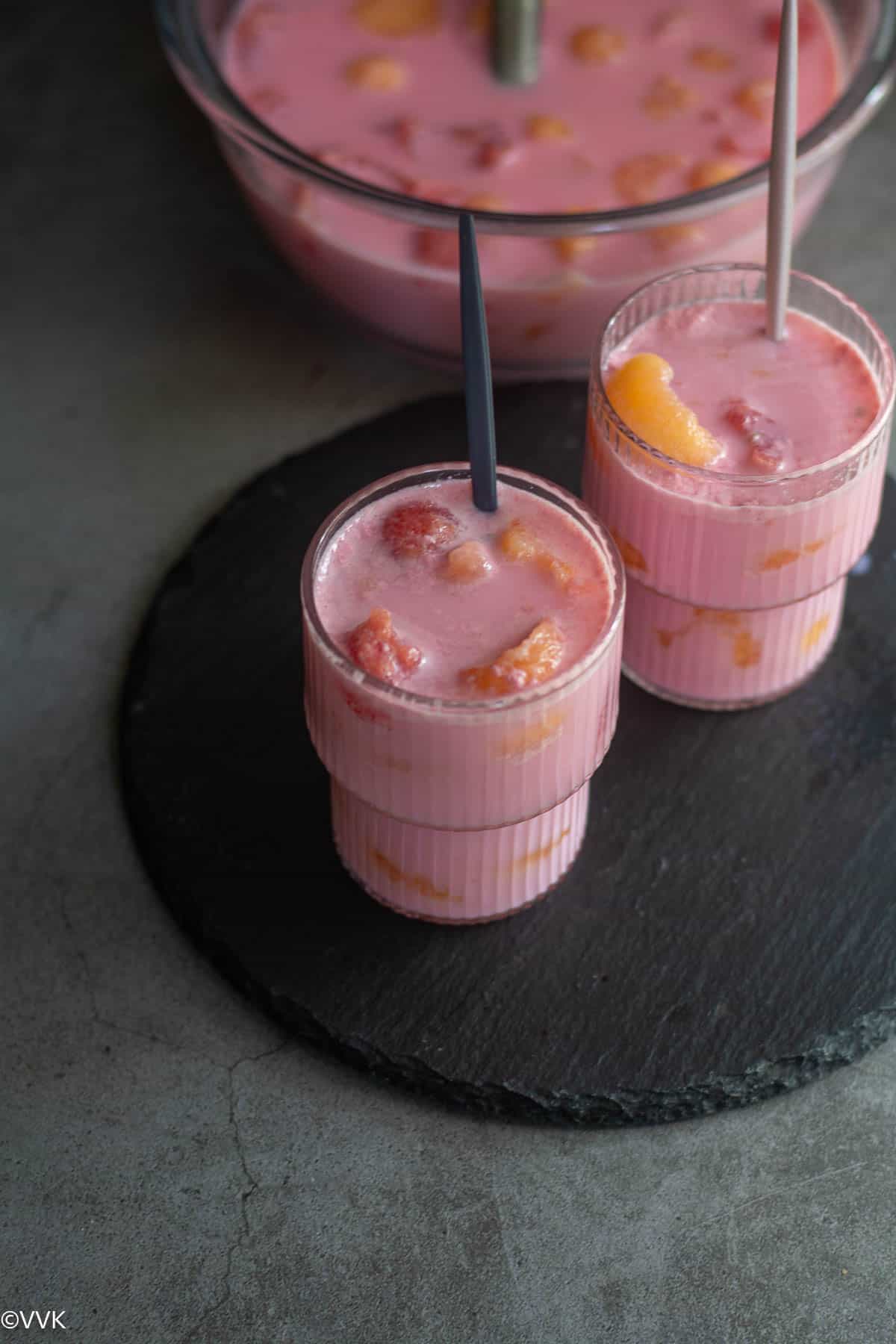 Rose milk melon Hwachae served in two glasses with spoon and one big bowl behind