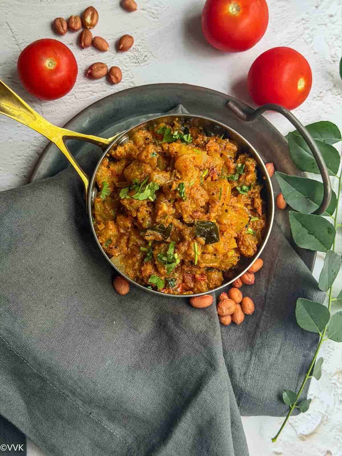 sorakkai verkadai masala with tomatoes on the side placed on top of the gray towel