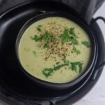 square image of bottle gourd soup served in black bowl