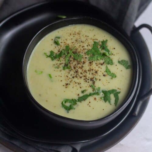 square image of bottle gourd soup served in black bowl